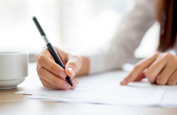 Hand of businesswoman writing on paper in office